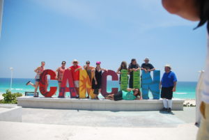 people standing by the Cancun sign