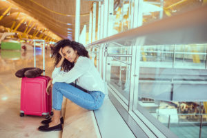Frustrated woman at airport realizing she should have purchased travel insurance for her vacation rental.