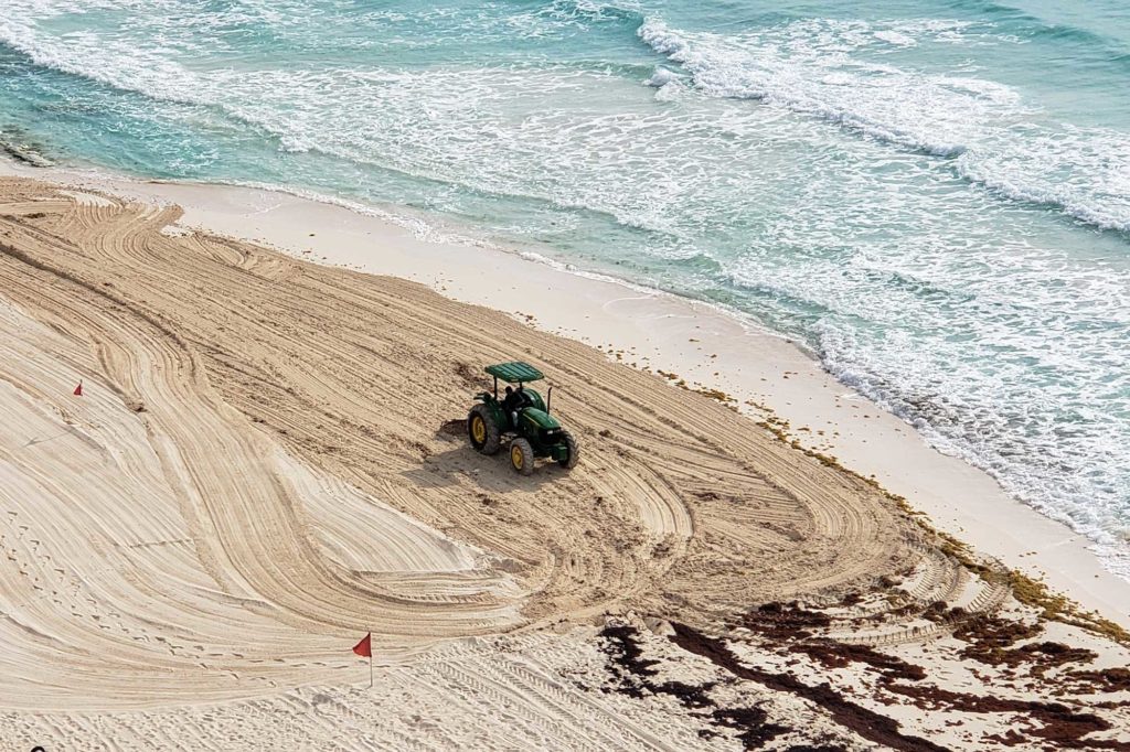 tractor cleaning the beach in cancun