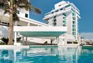 A luxurious penthouse balcony in Cancun with elegant outdoor furniture and a stunning view of the turquoise Caribbean Sea under a clear, sunny sky.