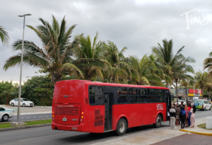 ADO Red SEA bus R1 in Cancun stopped outside Tim's Ocean Condos, showcasing public transit options for convenient transportation.