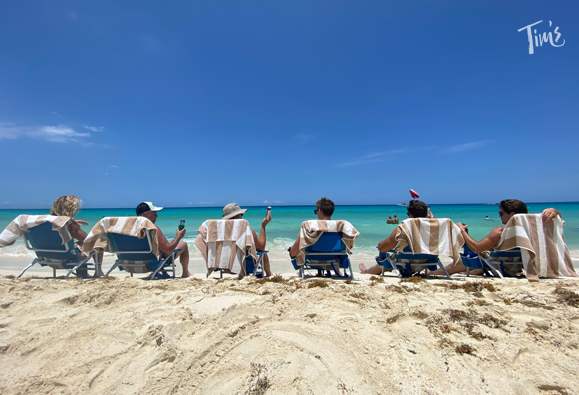 men sitting on lounge chairs on the beach