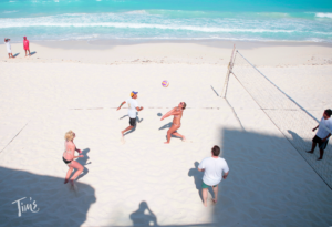 Spring break revelers playing volleyball on the beach by the ocean at Tim's Ocean Condos in Cancun, enjoying a lively and fun-filled day.