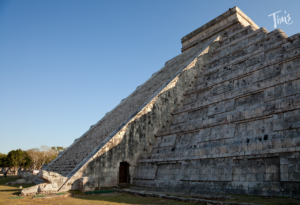 Chichen Itza pyramid during the fall equinox, with sunlight casting a serpent shadow on the steps, showcasing ancient Mayan architecture and astronomical alignment.