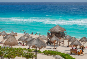 Playa Delfines in Cancun featuring the ocean, sandy beach, and palapas for shade.