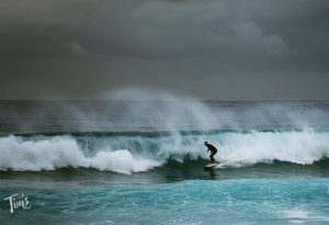 A man surfing on the ocean in Cancun before a hurricane warning, enjoying the waves under cloudy skies.