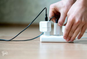 Hand inserting electronic plug into a surge protector, protecting electronics while in Mexico at a Cancun vacation rental.