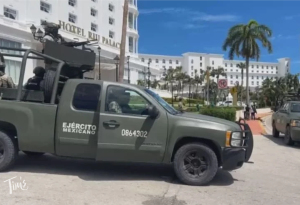 Police trucks and cars block the entrance of Hotel RIU Palace in Cancun after gunmen shot a man on the beach and escaped on jet skis.