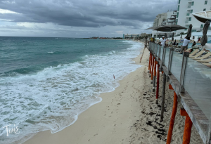 ÓLEO Cancún Playa® Beach with limited lounge chair space after Hurricane Helene, red flag indicating no swimming.