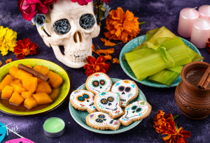 Traditional Day of the Dead food in Cancun featuring Pan de Muerto, tamales, and sugar skulls displayed on a colorful table.