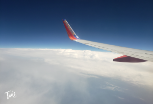 Southwest Airlines wing flying over white clouds toward Tim's Ocean Condos in Cancun, featuring the latest CHASE Southwest Airlines Rapid Rewards Credit Card promotions in this news article.