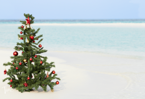 Christmas tree decorated with festive ornaments on the sandy beach of Tim's Ocean Condos in Cancun, Mexico, with ocean waves in the background