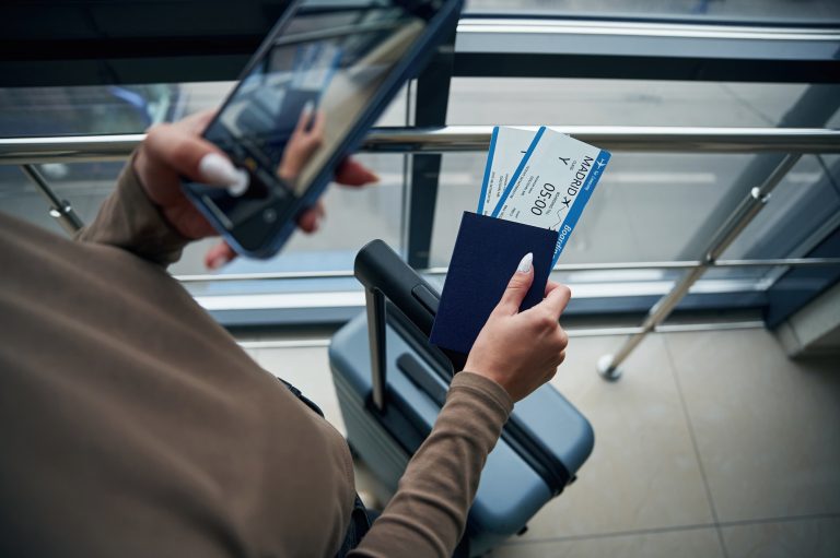 Woman at Cancun Airport holding airline tickets, verifying VISITAX payment was made and ensuring Mexico Departure Tax is included on her airline ticket.