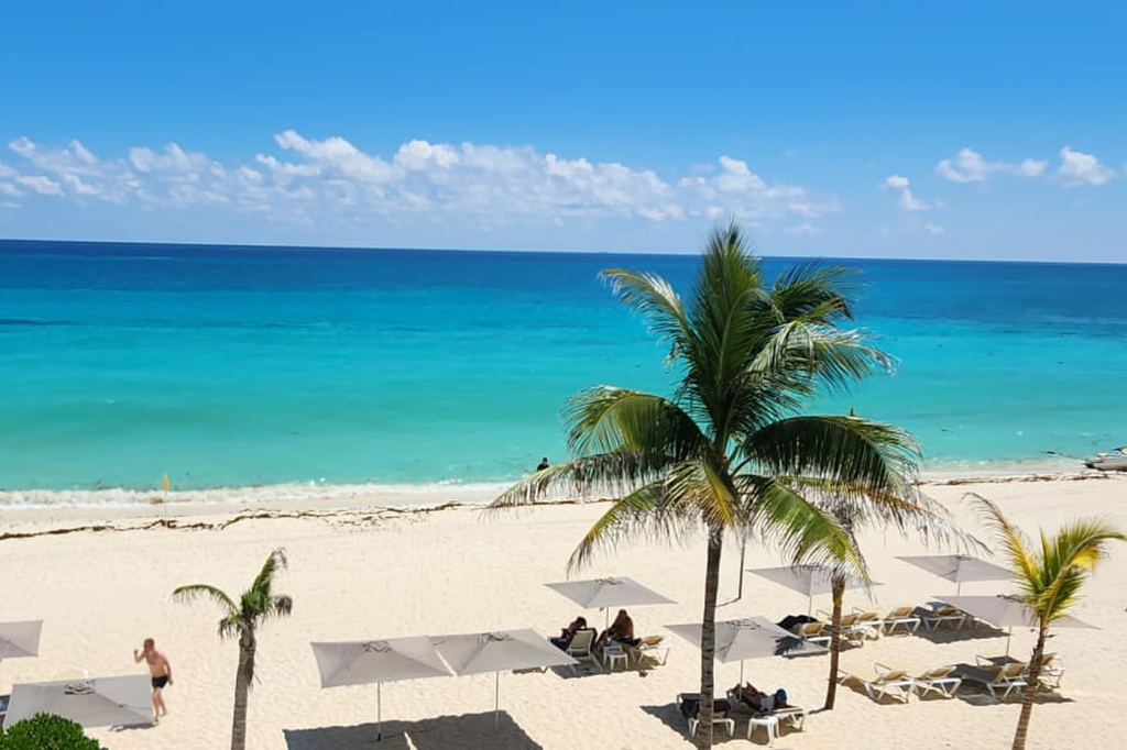 Private Cancun beach at Tim’s Ocean Condos with turquoise waters, a navy blue horizon, and powder-soft white sand—perfect for a beachfront vacation.