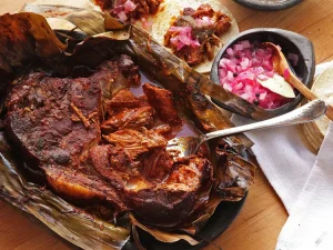 A plate of Cochinita Pibil in Cancun, featuring slow-roasted pork marinated in achiote and citrus, served with pickled red onions and corn tortillas.