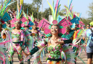 A vibrant Carnival dancer walks in the parade in Cancun, wearing a bright, colorful costume with intricate Mexican designs, capturing the festive energy of the celebration.