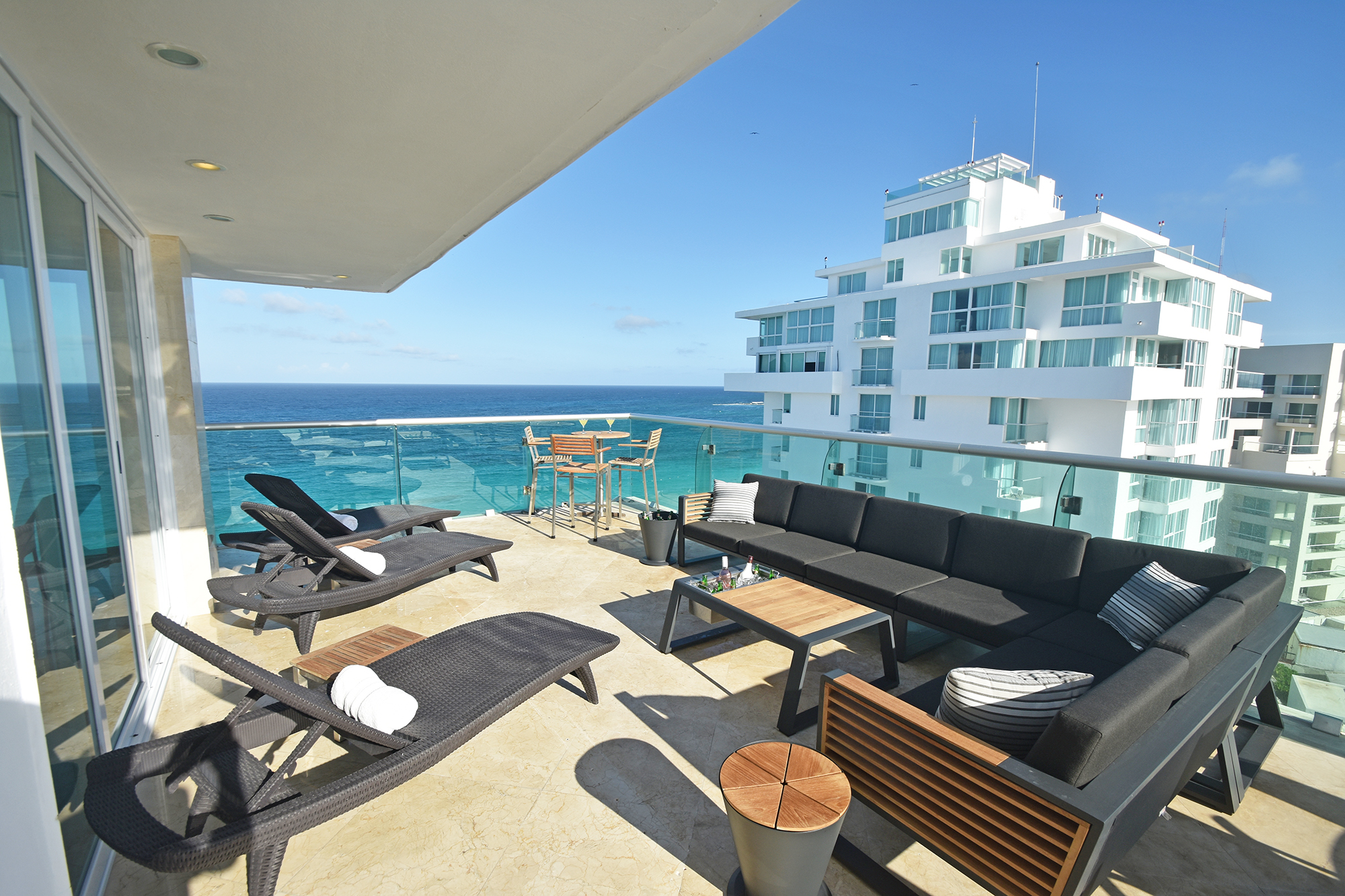 Penthouse 2701 balcony at Tim’s Ocean Condos with lounge chairs, outdoor sofa, and dining table for ten overlooking turquoise Caribbean waters.