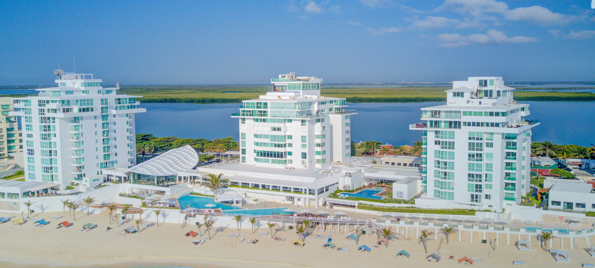 Oceanfront view of Tim’s Ocean Condos resort in Cancun showing pool, beach, and buildings