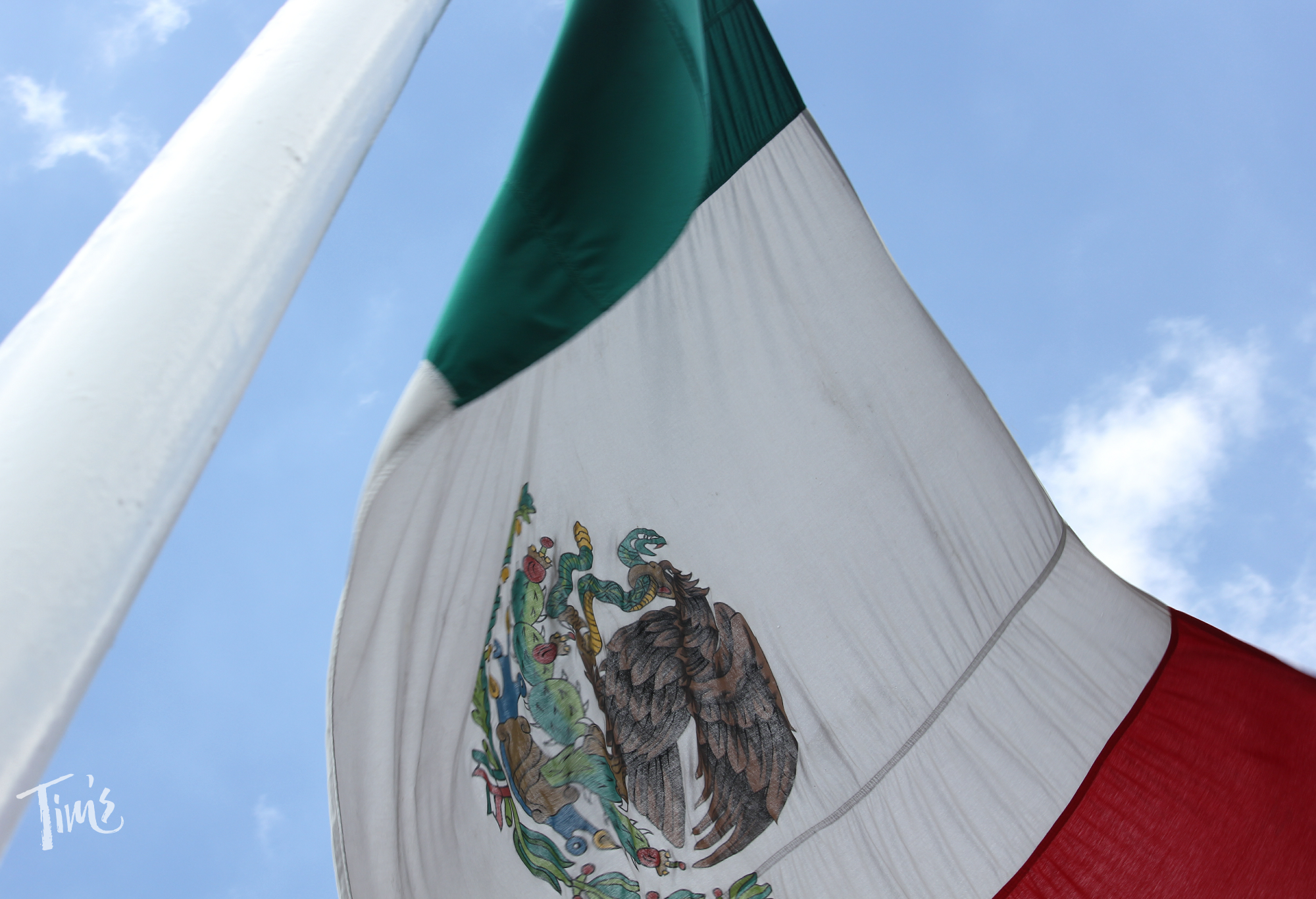 Mexico flag flying high at Tim’s Ocean Condos resort with blue sky in the background.