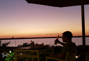 Man lifting a beer at Mangroove Sunset Grill after sunset over the Nichupté Lagoon in Cancun