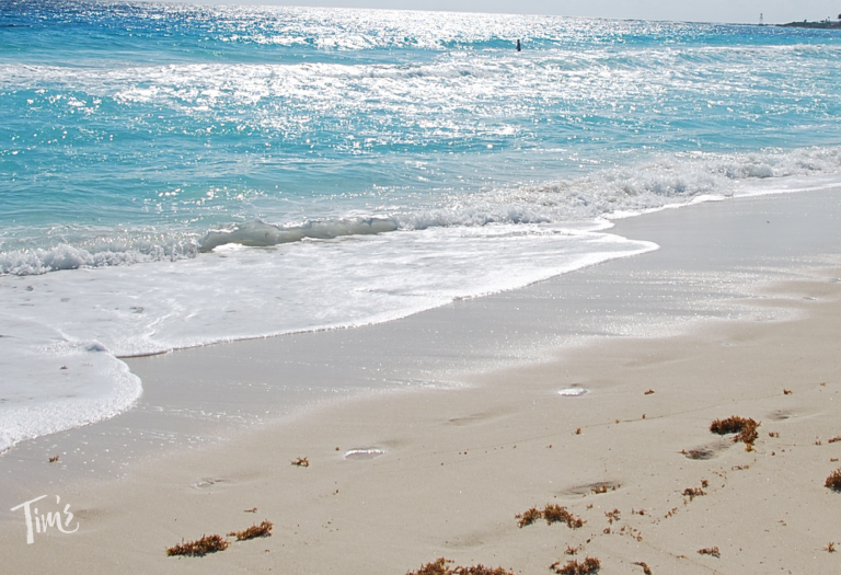 Calm Caribbean ocean and sandy beach with footprints in Cancun during travel update 2026 near Tim’s Ocean Condos vacation rentals in Cancun.