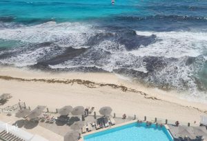 Cancun beach conditions March 2026 view from penthouse at Tim’s Ocean Condos showing ocean, pool, and clean shoreline