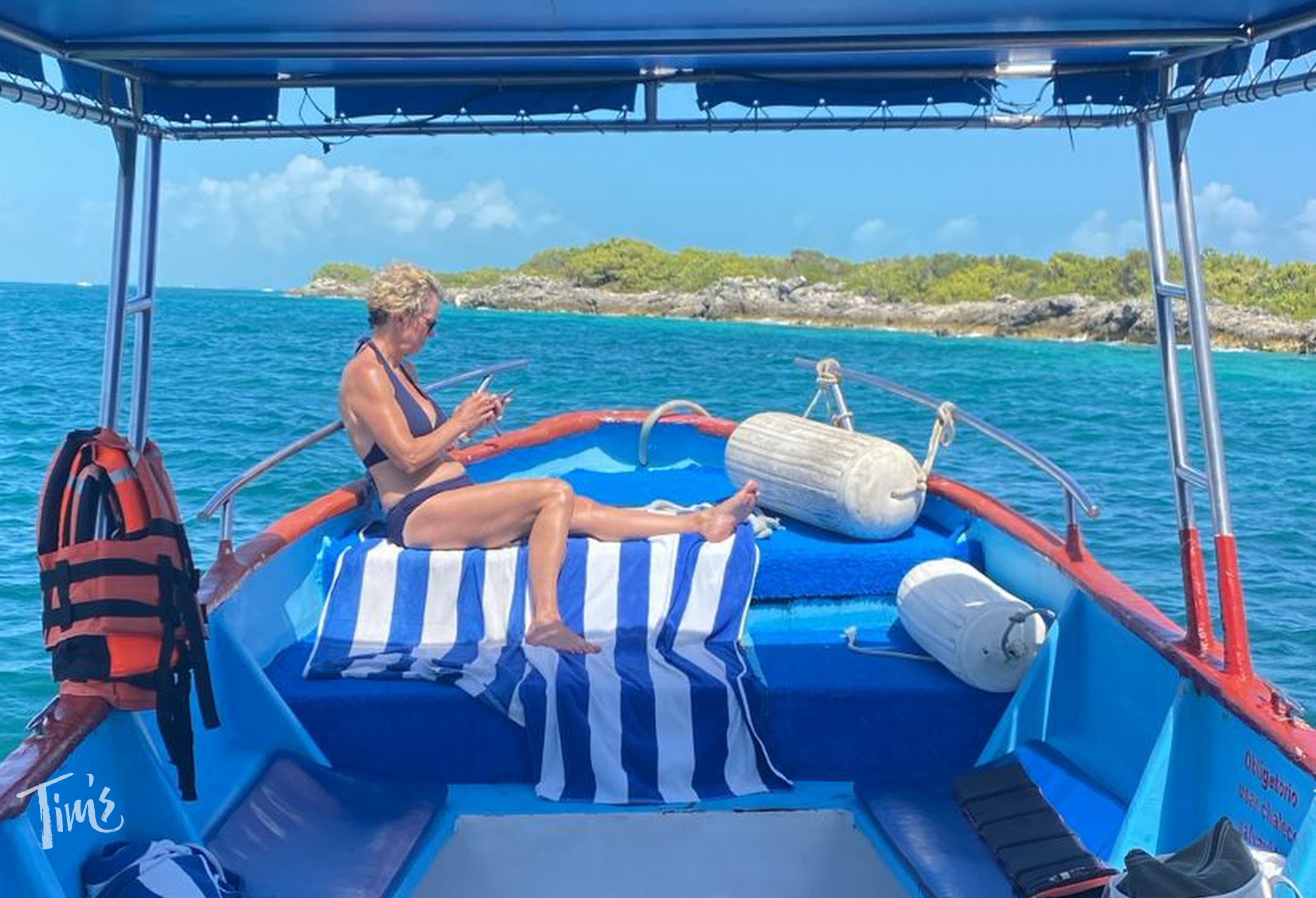 Mom sunbathing on snorkeling boat while family snorkels Isla Mujeres Cancun