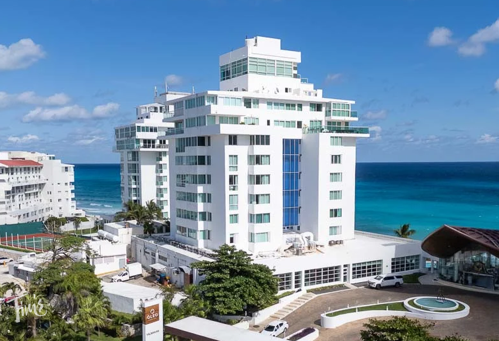 Oleo Cancun Resort entrance and oceanfront tower, with the curved brown lobby roof visible on the right.