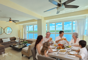 Family sharing Thanksgiving dinner around the dining table in Penthouse 3703 at Tim’s Ocean Condos, with lagoon views.
